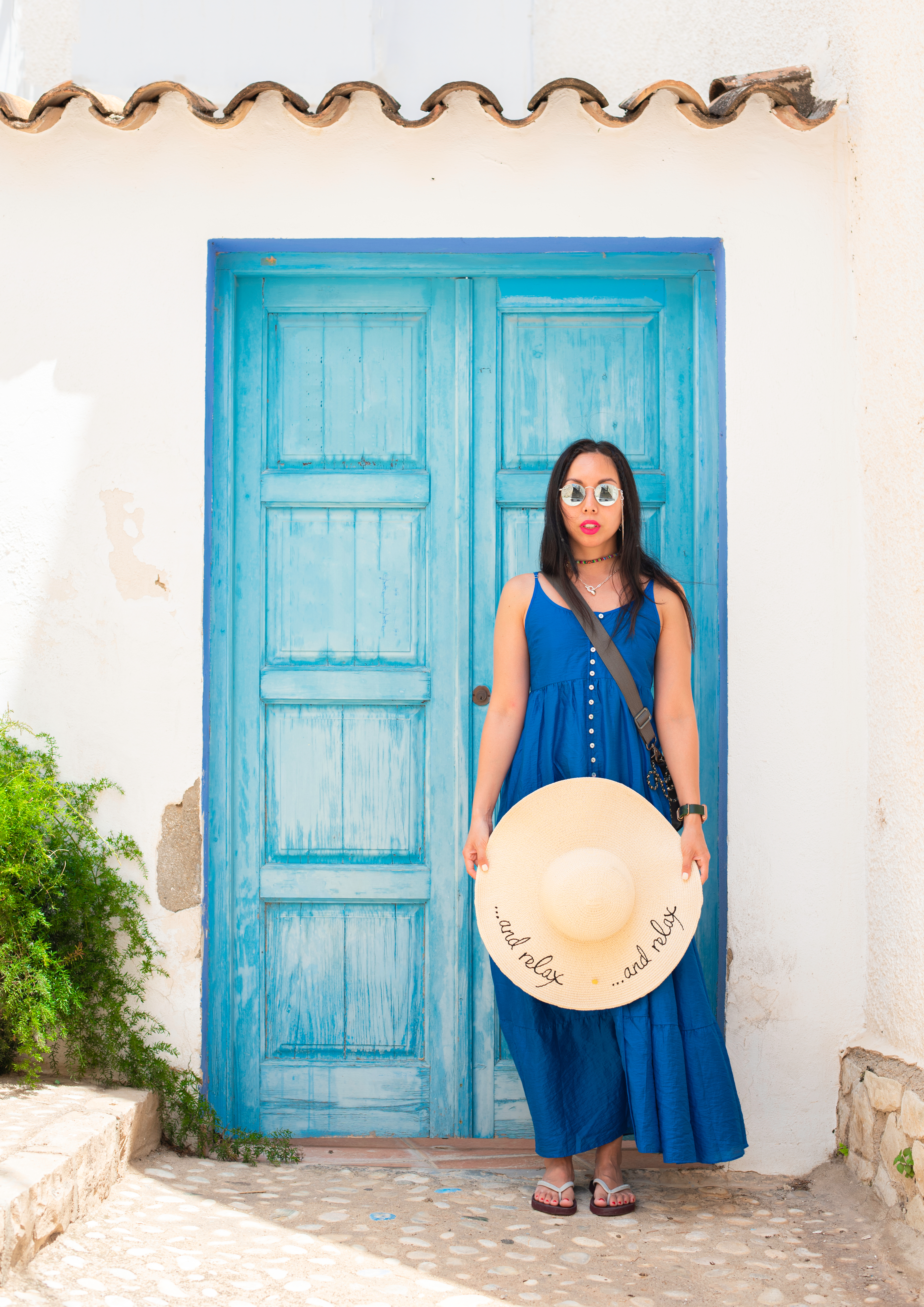 a girl in a blue long dress standing in front of the blue wood door